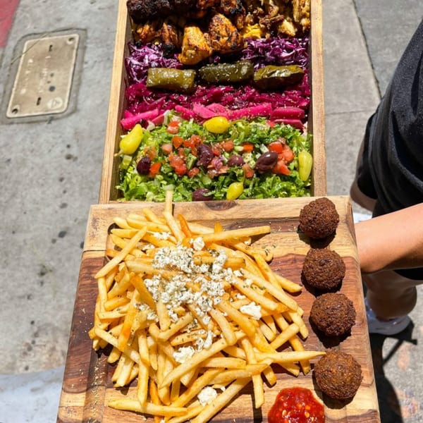 Killer Kabab's large wooden platter with kebabs, salad, fries with feta, falafel, and sauce.