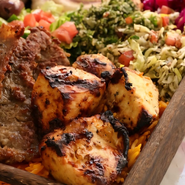 Grilled chicken and beef kebabs with rice and fresh salad in a wooden tray.