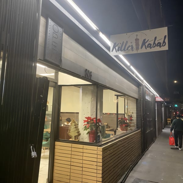 Killer Kabab storefront at night with a person walking by, showing interior decorations.