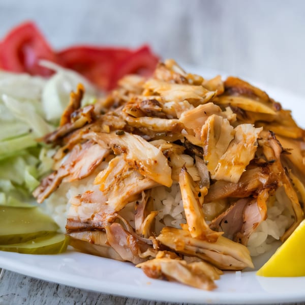 Killer Kabab's chicken kebab plate with rice, lettuce, tomatoes, pickles, and a lemon wedge.