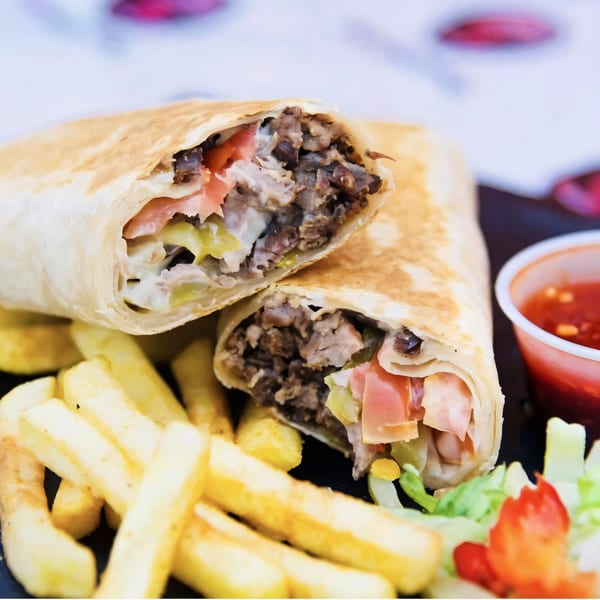 Two Killer Kabab wraps, cut in half, with fries, salad, and a side of red sauce.