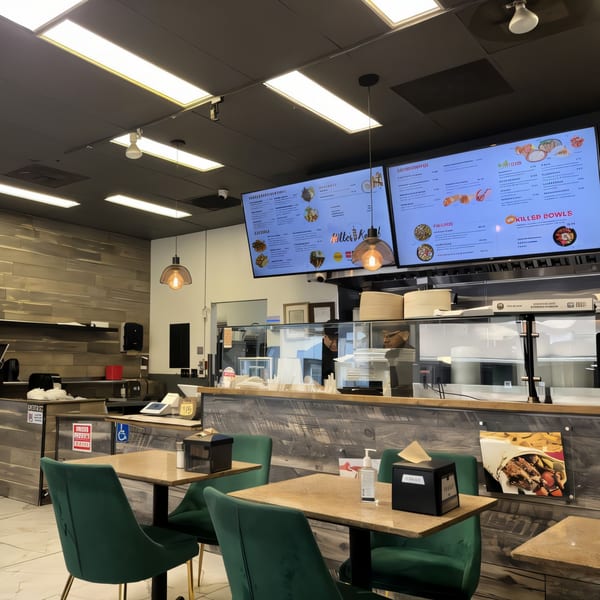Interior of Killer Kabab restaurant with digital menus, wooden walls, and green chairs at tables.