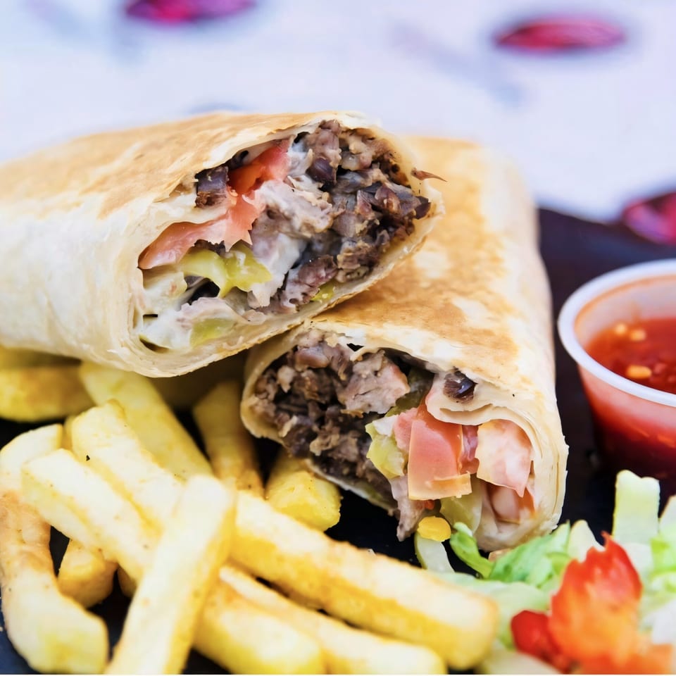 Two Killer Kabab wraps, cut in half, with fries, salad, and a side of red sauce.