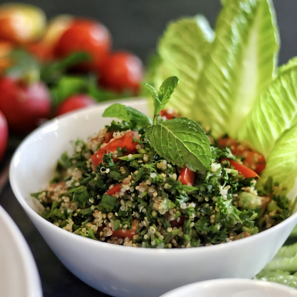 Killer Kabab's fresh quinoa tabbouleh salad with tomatoes, parsley, and mint in a white bowl.