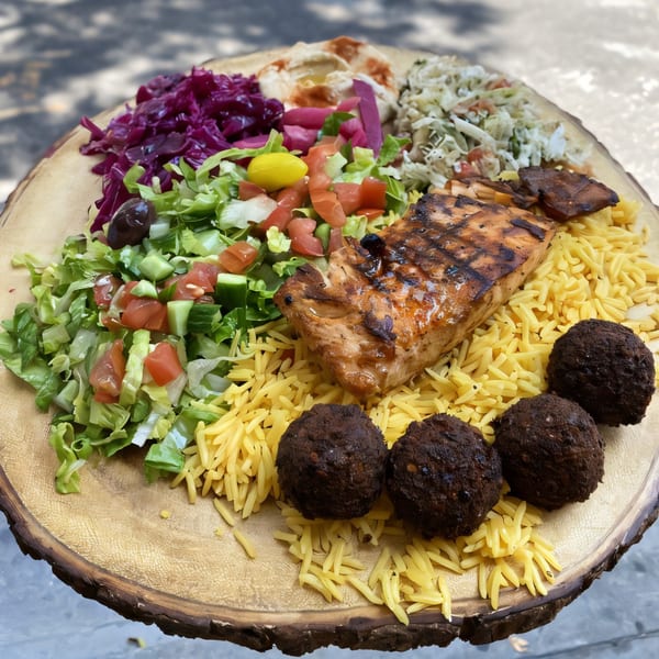 Grilled salmon, falafel, rice, and various salads on a wooden platter from Killer Kabab.