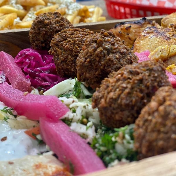 Close-up of Killer Kabab's falafel, pickled pink turnips, and red cabbage, with fries in the background.